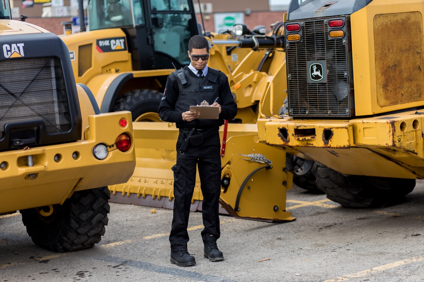Security guard recording site observations beside heavy equipment
